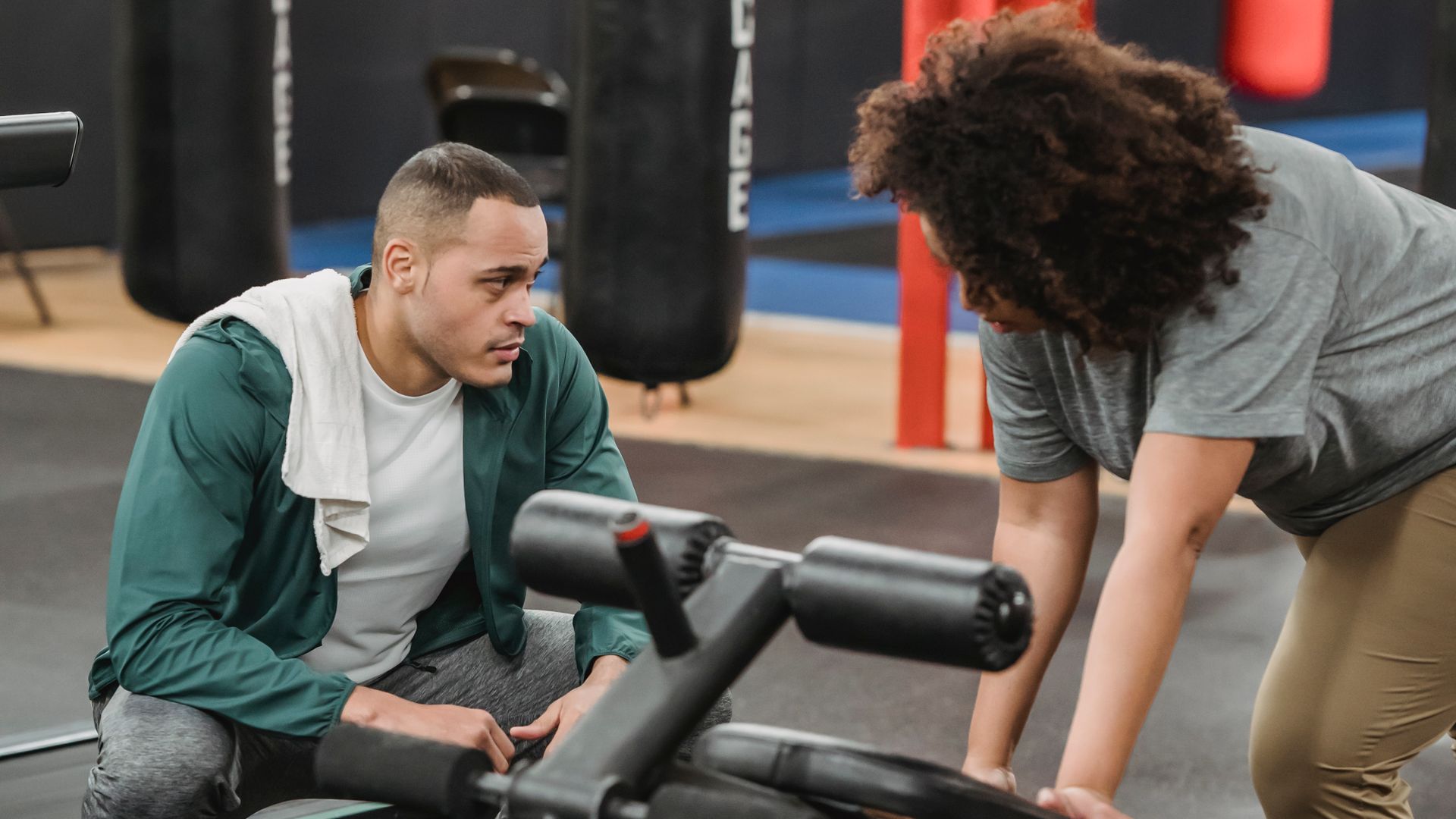 A personal trainer coaching a client through an exercise in a bright gym